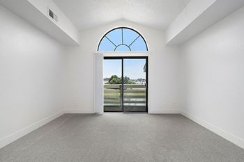 A living room with a large arched window and cathedral ceiling with a view 