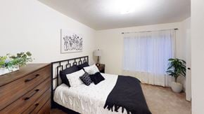 Perrysburg apartment for rent - A bedroom with a bed, nightstand, and a potted plant at Tracy Creek Apartment Homes in Perrysburg, OH