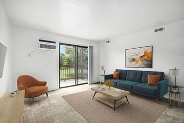 Lansing apartment for rent - A living room with a blue couch, a chair, a coffee table, and a painting on the wall.