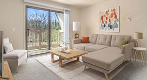 Portage apartment for rent - A living room with a grey couch, a wooden coffee table, and a painting on the wall at Walnut Trail Apartments in Portage, MI