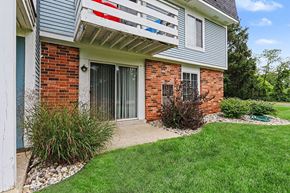 Portage apartment for rent - A building with a red brick wall and a white patio at Walnut Trail Apartments, Michigan