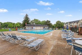 Lansing apartment for rent - A pool surrounded by chairs and a large sundeck at Waverly Park Apartments, Lansing