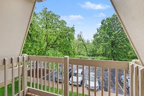 Lansing apartment for rent - A balcony with a view of a parking lot and trees at Waverly Park Apartments, Lansing