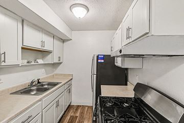 Lansing apartment for rent - A kitchen with white cabinets and a black refrigerator.