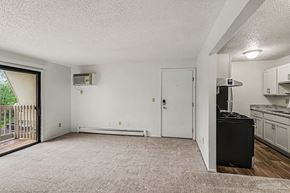 Lansing apartment for rent - A living room with sliding glass doors to a balcony and an upgraded kitchen at Waverly Park Apartments, Lansing