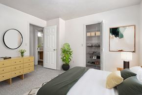 Elkhorn apartment for rent - A bedroom with a bed, dresser, and a walk-in closet with wardrobe organizers at West Hampton Park Apartments in Elkhorn, NE 68022