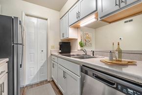 Fort Wayne apartment for rent - A kitchen with white cabinets and a black refrigerator at West Wind Apartments, Fort Wayne, 46808