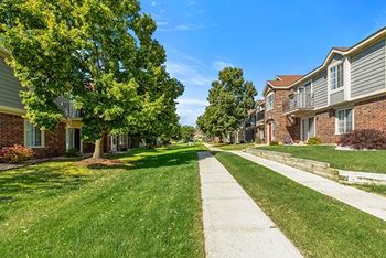 A grassy courtyard with trees and a sidewalk