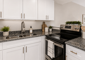 Gainesville townhouse for rent - A modern kitchen with white cabinets and a black stove top oven.