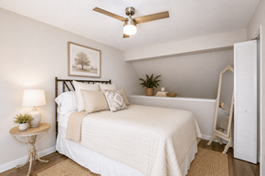 Gainesville townhouse for rent - A bedroom with a bed, a ceiling fan, and a nightstand with a lamp.