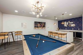 Gainesville apartment for rent - A pool table with a blue cloth and a cue stick on it.