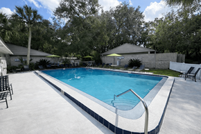 Gainesville apartment for rent - A swimming pool surrounded by trees and a white fence.