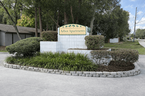 Gainesville apartment for rent - A sign for Arbor Apartments is surrounded by bushes and trees.