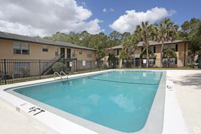 Jacksonville apartment for rent - A swimming pool in a residential area with apartment buildings in the background.