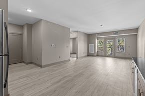 Holt apartment for rent - A spacious room with wooden flooring and a large window with a view of trees.