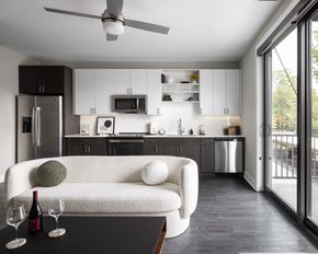 Ferndale apartment for rent - A modern kitchen with a white couch and a ceiling fan.at Flats at Iron Ridge, Michigan, 48220
