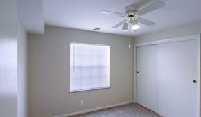 Columbus apartment for rent - Bedroom with white walls, grey carpet, white closets, a large window, and a ceiling fan.