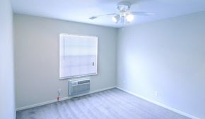 Columbus apartment for rent - Bedroom with white walls, grey carpet, a ceiling fan, large window, and AC unit.