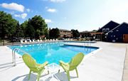 Oak Park apartment for rent - Two green chairs are placed on the edge of a blue swimming pool.