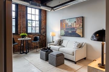 Detroit apartment for rent - A living room with a white couch and a painting of a car on the wall.