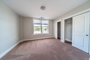 Gahanna apartment for rent - Bedroom with large window, beige plush carpeting, double closets, and tan walls.
