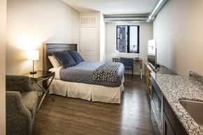 Duluth apartment for rent - A bedroom with a bed, chair, and window.