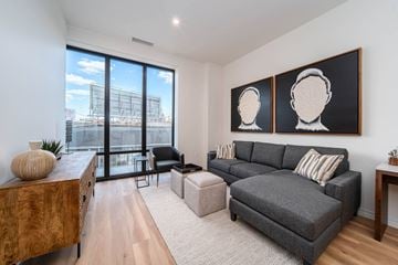 Detroit apartment for rent - a living room with a gray couch and a large window