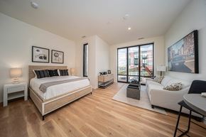 Detroit apartment for rent - a bedroom with a bed and a couch and a large window