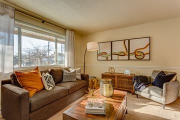 Euclid apartment for rent - A living room with a brown couch, a coffee table, and a large abstract painting on the wall.
