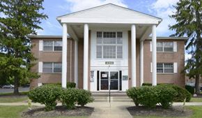 Columbus apartment for rent - Exterior of Alexander Hamilton Plaza Apartments with green bushes in front
