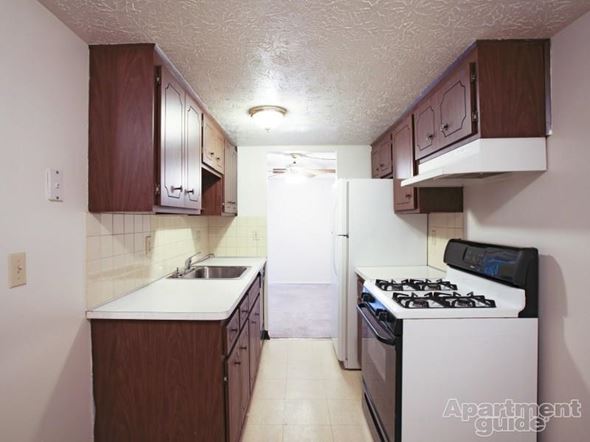 Elyria apartment for rent - Dark kitchen cabinetry with beige tile flooring, and white appliances with black accents.