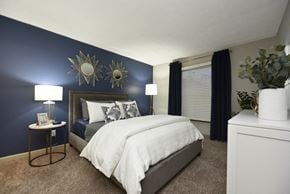 Indianapolis apartment for rent - a bedroom with a blue accent wall and a white bed