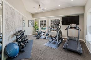 Grand Blanc apartment for rent - a gym with cardio equipment and a tv on the wall