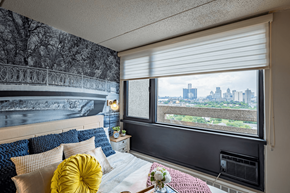 Detroit apartment for rent - a bedroom with a bed and a window overlooking a city at City Club Apartments Lafayette Park, Detroit, Michigan