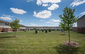 Indianapolis apartment for rent - A grassy field with trees and a building in the background.