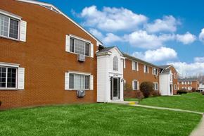 Romulus apartment for rent - Red brick apartment buildings with blue clouded sky and green grass
