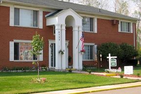 Romulus apartment for rent - Red brick building with white pillar entrance.