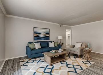 Oklahoma City apartment for rent - A living room with a blue couch, a coffee table, and a painting on the wall.