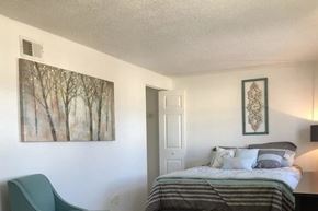 Indianapolis apartment for rent - A bedroom with a bed, chair, and artwork on the wall.
