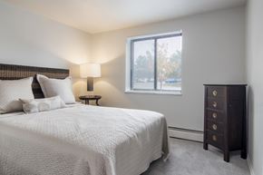 Bedford apartment for rent - A bedroom with a large bed and a nightstand with a lamp.
