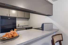 Bedford apartment for rent - A kitchen with a black refrigerator, a counter with a plate of food on it, and a chair.