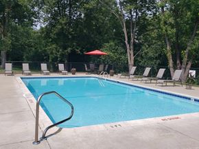 Waterford apartment for rent - Rectangle pool with brown lawn chaairs, table with 4 chairs and red umbrella in back corner