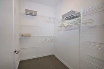 A walk in closet with white walls and shelves