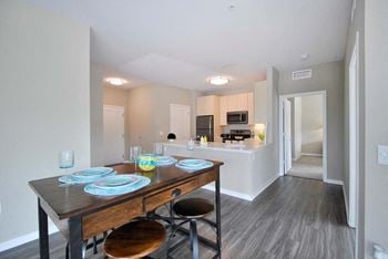 A dining area with a table and chairs and a kitchen in the background