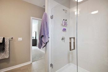 A bathroom with a glass shower door and a purple towel