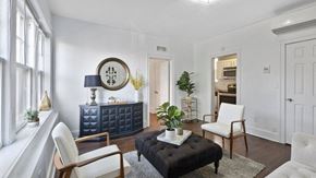 Detroit apartment for rent - a living room with white walls and a black ottoman