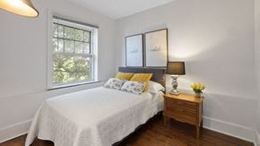 Detroit apartment for rent - A bedroom with a bed, nightstand, and window.