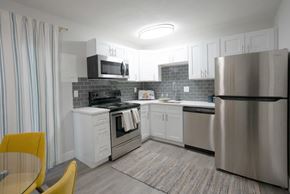St. Louis apartment for rent - A modern kitchen with a yellow chair and a stainless steel refrigerator.