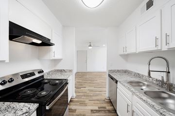 Fort Worth apartment for rent - A kitchen with a black stove top oven and white cabinets.