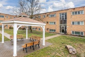 Cincinnati apartment for rent - A white pavilion with benches is in front of a brick building.